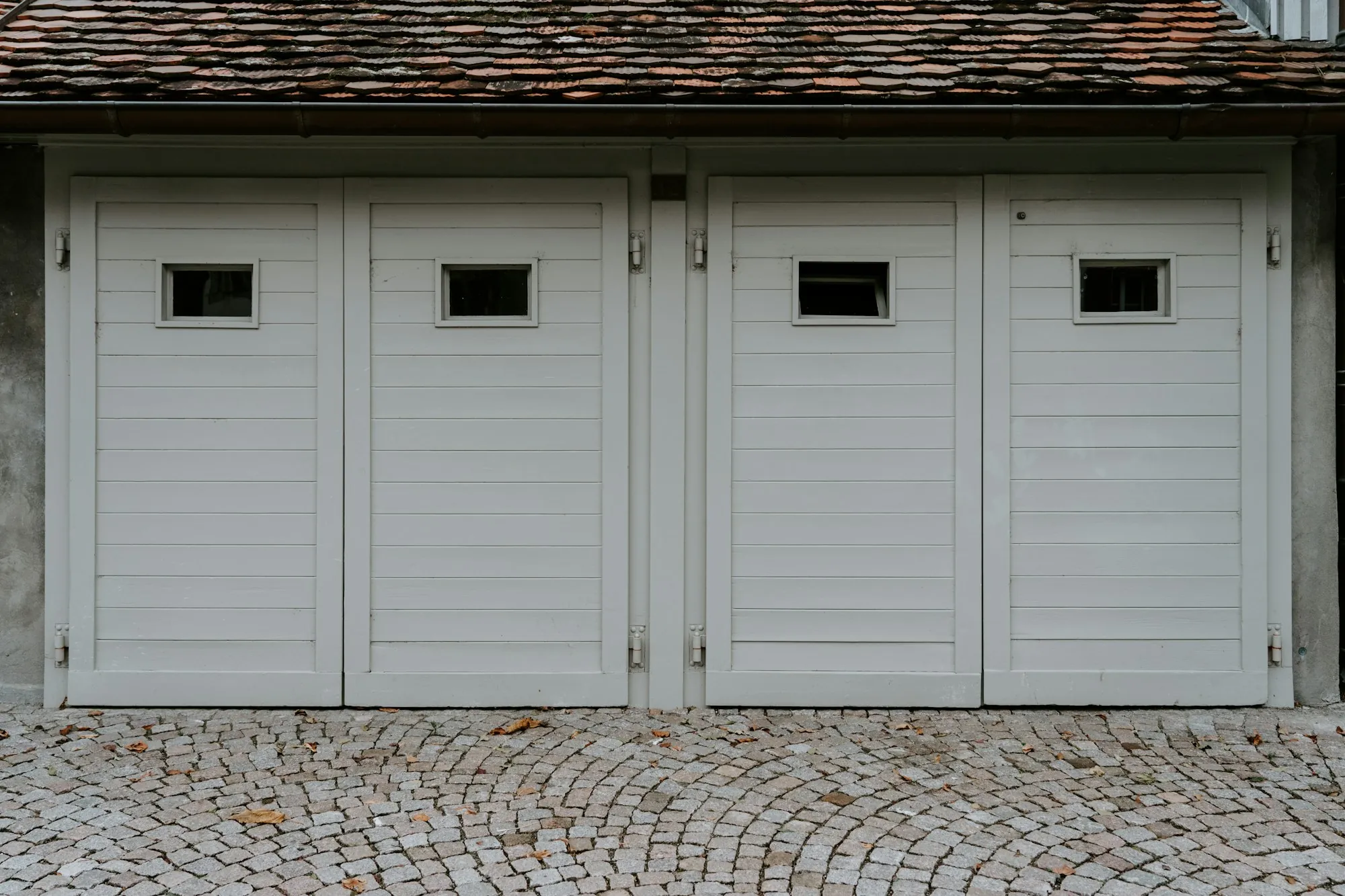 Row of closed white wooden garage doors with small windows