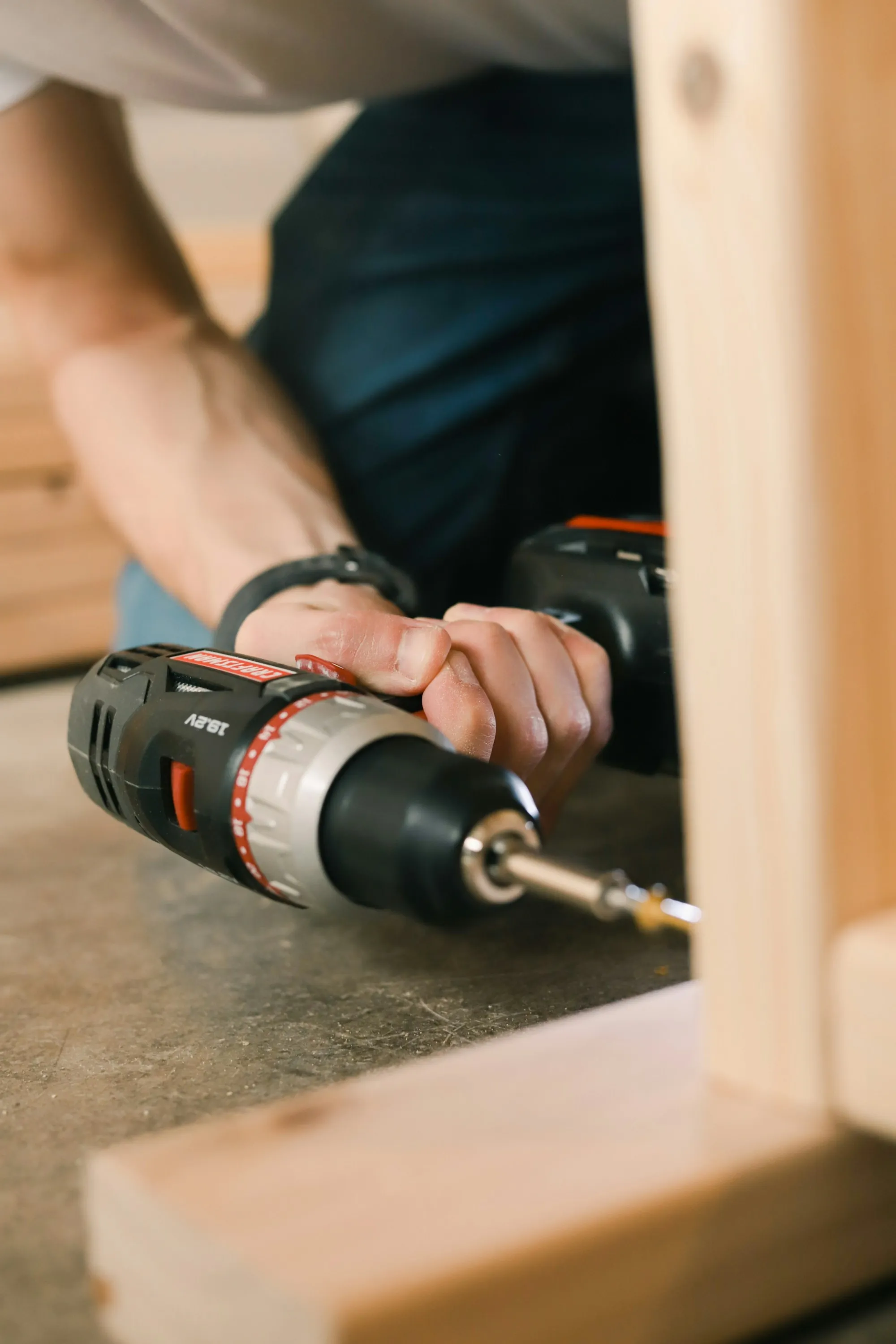 Hands using a cordless drill on a wooden board