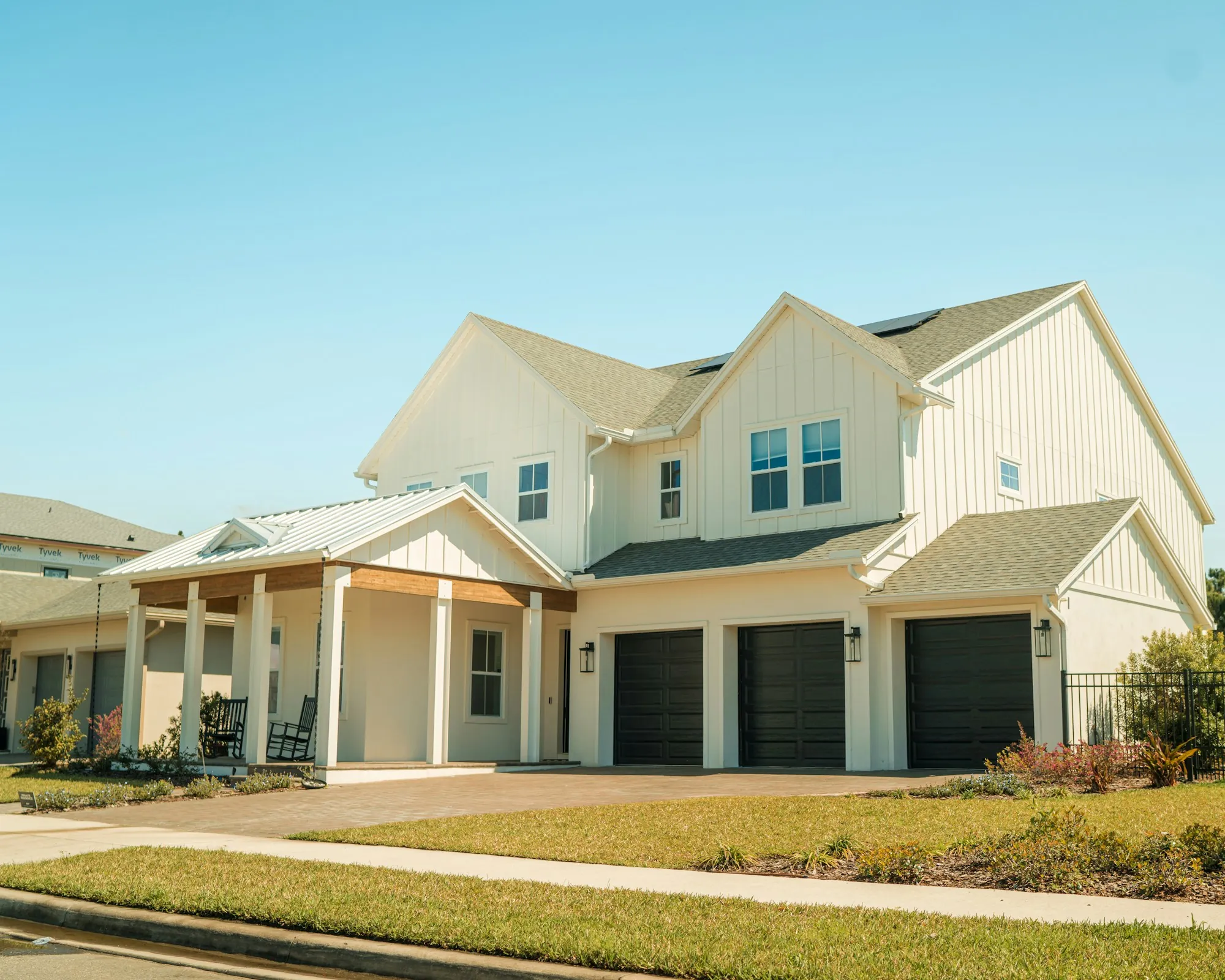 Large white two-story house with three garage doors