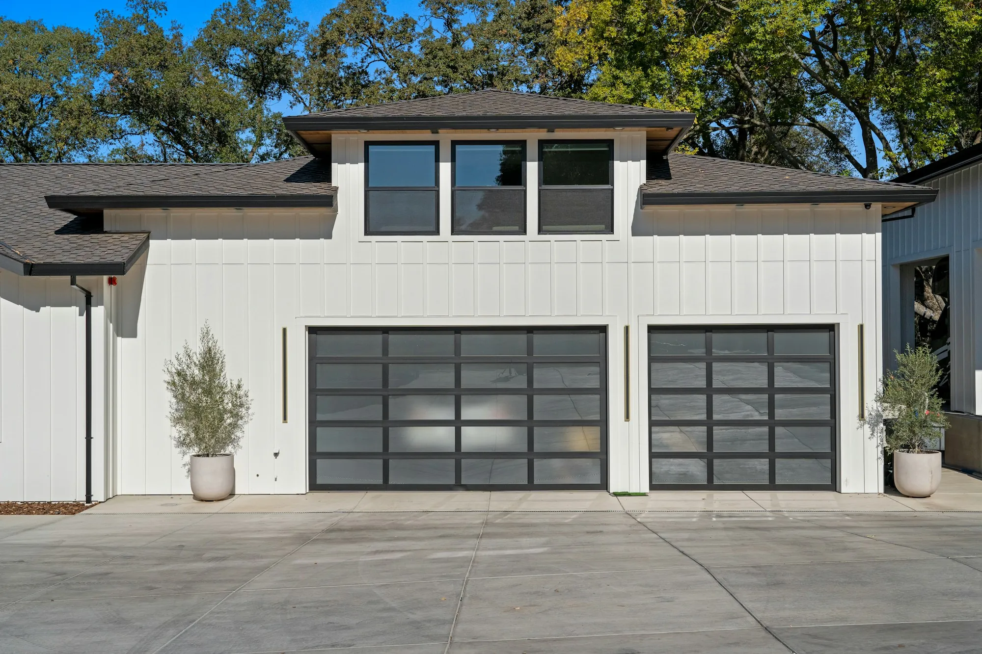 Two modern glass-panel garage doors on a white house