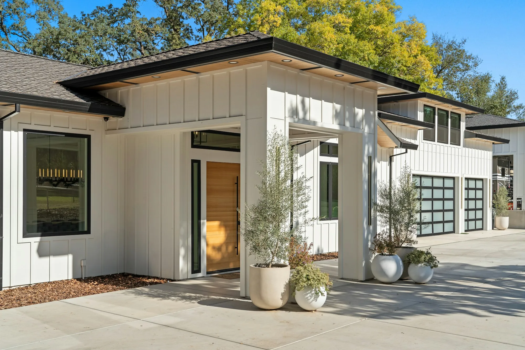 Modern white single-story home with glass-panel garage doors